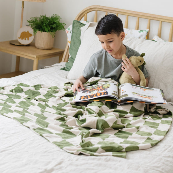 Boy reading in bed with olive checkered MINKY STRETCH RECEIVING BLANKETS - Saranoni