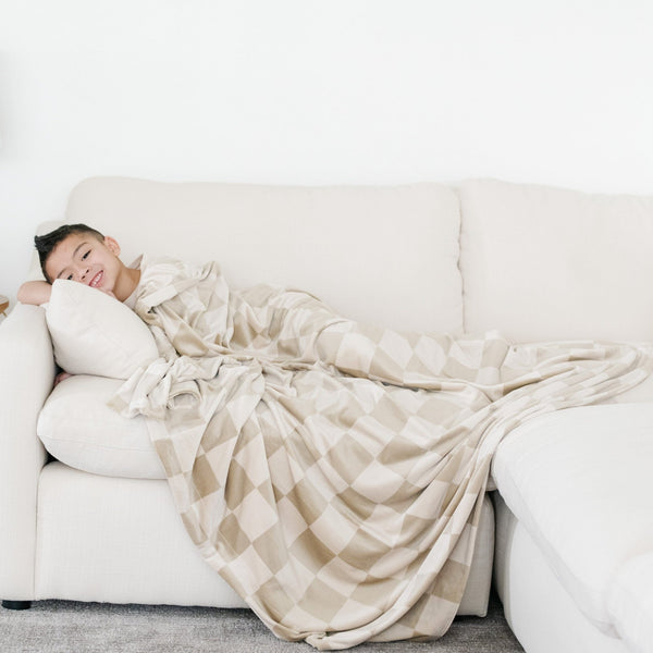 Boy laying down snuggling with checkered MINKY STRETCH THROW BLANKETS - Saranoni