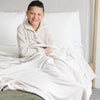 Boy sitting on bed with MINKY STRETCH THROW BLANKETS - Saranoni