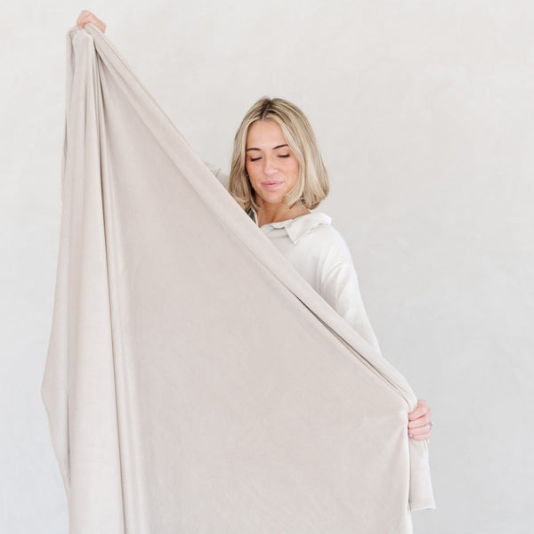 Woman holding out neutral color MINKY STRETCH THROW BLANKETS - Saranoni