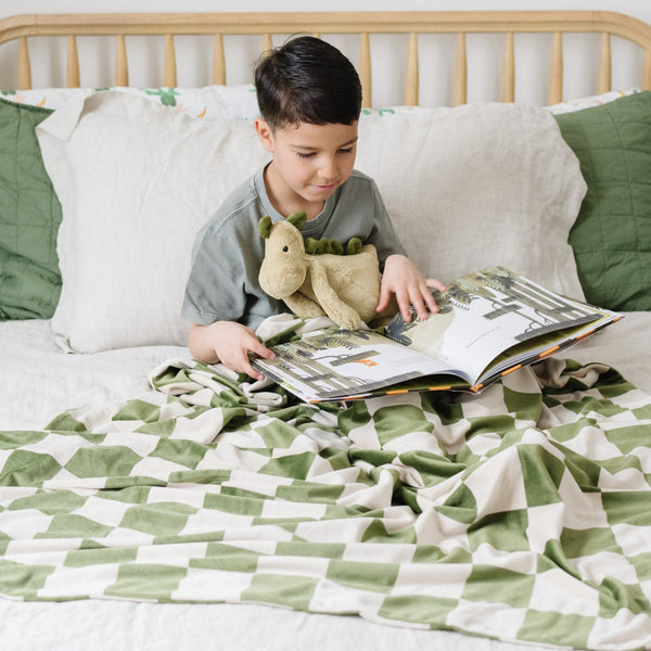 Boy reading in bed with Olive Green MINKY STRETCH THROW BLANKETS - Saranoni