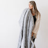 PATTERNED FAUX FUR THROW BLANKETS - Woman wrapped in a Saranoni blanket feeling the softness.