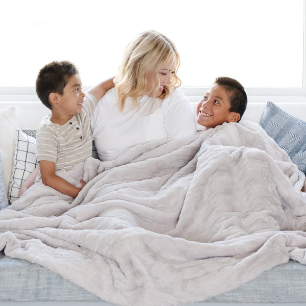 PATTERNED FAUX FUR THROW BLANKETS - Woman and her little boys wrapped in a luxurious Saranoni Throw Blanket