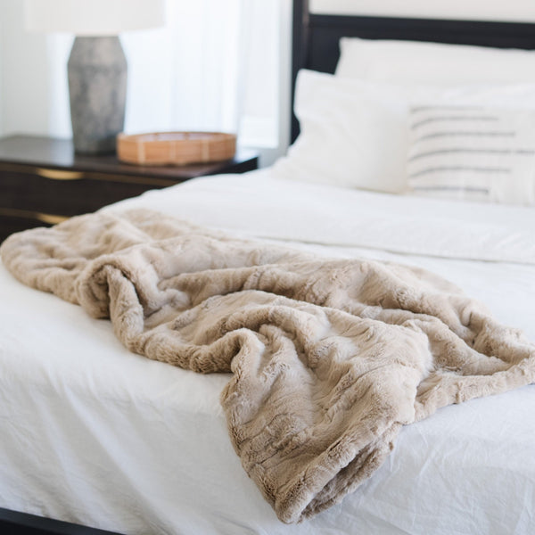 PATTERNED FAUX FUR THROW BLANKETS - Luxurious Saranoni blanket draped over a modern bedspread