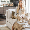 PATTERNED FAUX FUR XL THROW BLANKETS - Girl wrapped in a Saranoni blanket on the couch, feeling cozy and warm.