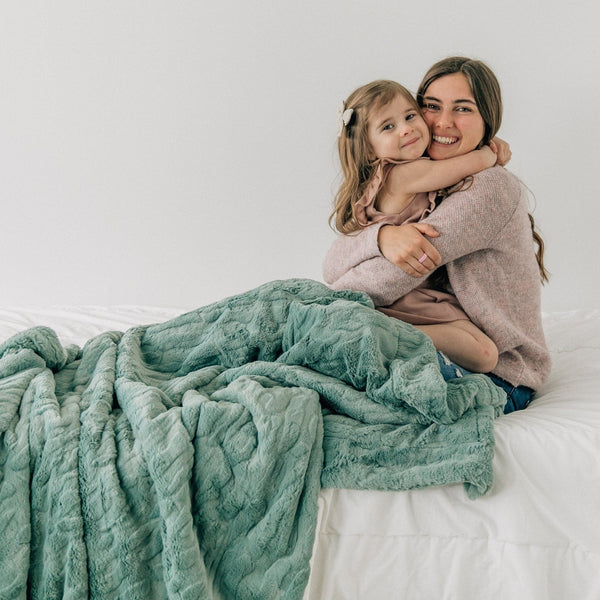 PATTERNED FAUX FUR XL THROW BLANKETS - Fluffy Saranoni blanket on a bed, providing warmth and comfort.