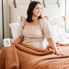 Woman snuggled in bed with a drink and cozy orange Ginger RIBBED BAMBONI KING BLANKETS - Saranoni