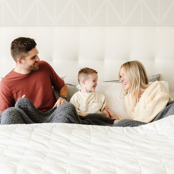 Family laughing and snuggling in bed together with comfy and soft Charcoal RIBBED BAMBONI KING BLANKETS - Saranoni