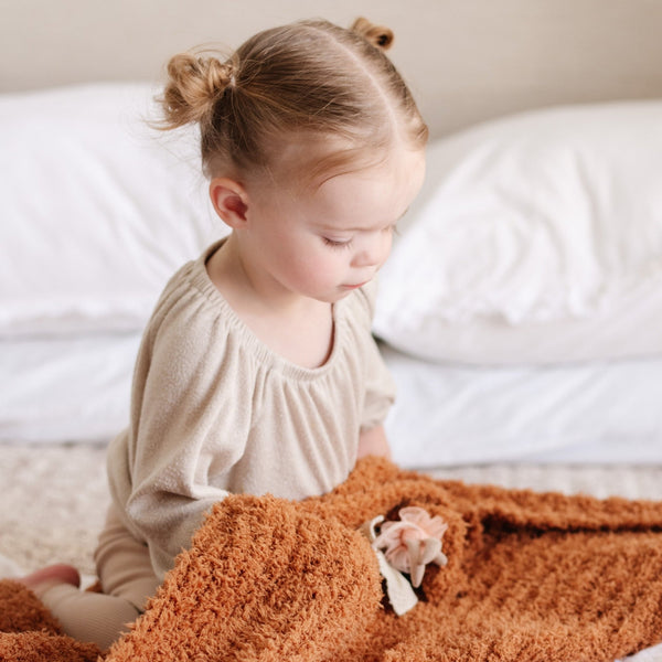 Little girl playing with her favorite extra soft Orange Ginger RIBBED BAMBONI MINI BLANKETS - Saranoni