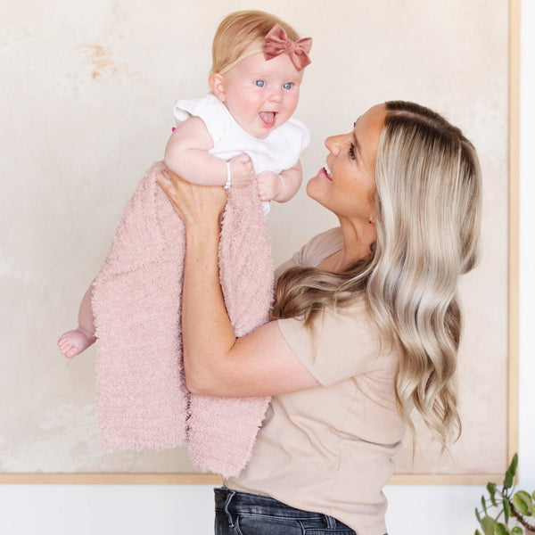 Mom holding up smiling baby in adorable and soft light pink Cameo RIBBED BAMBONI RECEIVING BLANKETS - Saranoni