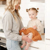 Mom and daughter in the kitchen with a beautiful and stretchy burnt orange GingerRIBBED BAMBONI RECEIVING BLANKETS - Saranoni