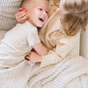 Little siblings laughing and playing with each other, wrapped in soft and cozy light gray Moonbeam RIBBED BAMBONI RECEIVING BLANKETS - Saranoni