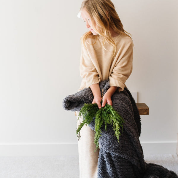 Little girl sitting on bench with super soft Charcoal RIBBED BAMBONI THROW BLANKETS - Saranoni