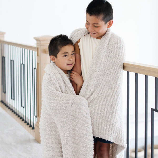 Young brothers wrapped together in light and breathable Light Gray Moonbeam RIBBED BAMBONI THROW BLANKETS - Saranoni