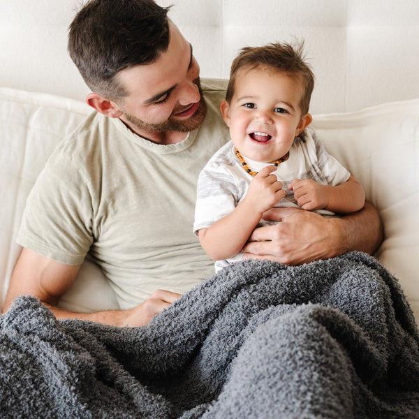 Dad and little boy snuggling and laughing with their Charcoal RIBBED BAMBONI THROW BLANKETS - Saranoni