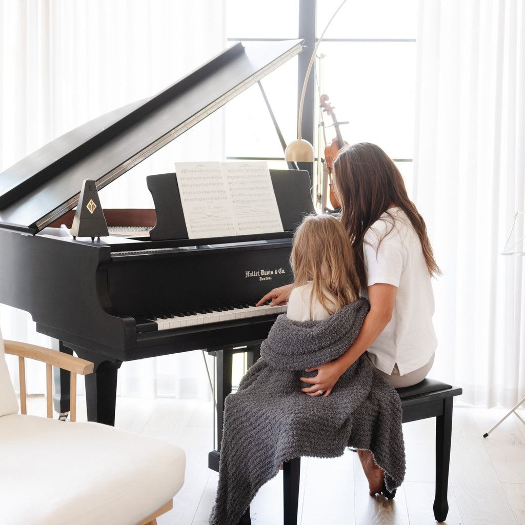 Sisters playing piano together, wrapped in Charcoal RIBBED BAMBONI THROW BLANKETS - Saranoni