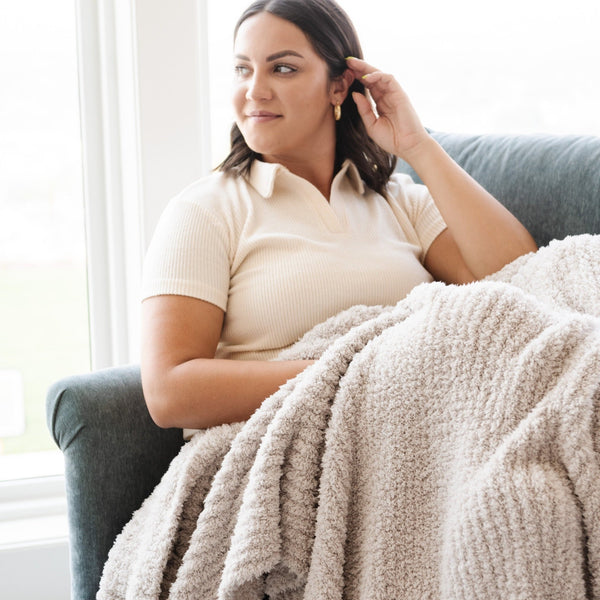 Woman sitting with her favorite lightweight Light Gray Moonbeam RIBBED BAMBONI THROW BLANKETS - Saranoni