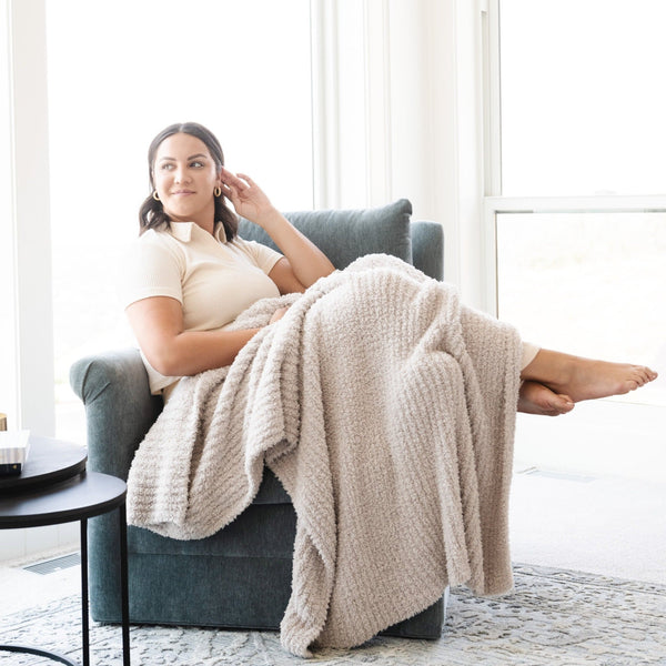 Woman relaxing on chair with super soft and stretchy Light Gray Moonbeam RIBBED BAMBONI THROW BLANKETS - Saranoni