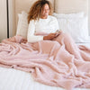 Woman relaxing in bed with beautiful Light Pink Cameo RIBBED BAMBONI THROW BLANKETS - Saranoni