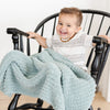 Little boy rocking in chair, sitting with super soft and comfy light blue Surf RIBBED BAMBONI TODDLER BLANKETS - Saranoni