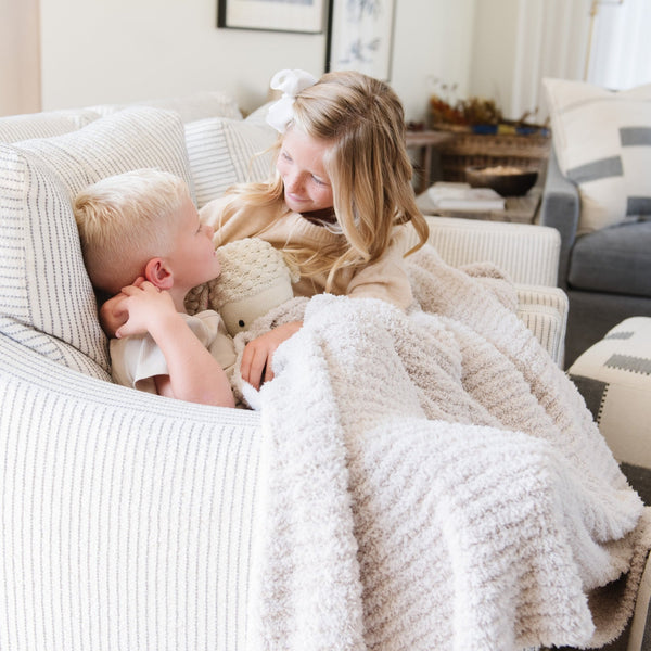 Little siblings snuggling together on the couch, wrapped in extra soft and stretchy Light Gray Moonbeam RIBBED BAMBONI TODDLER BLANKETS - Saranoni