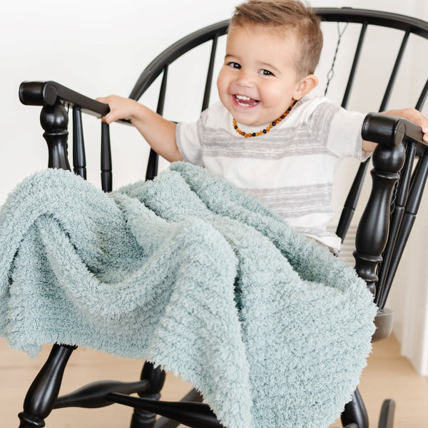 Little boy on a rocking chair, wrapped in light blue Surf RIBBED BAMBONI TODDLER BLANKETS - Saranoni