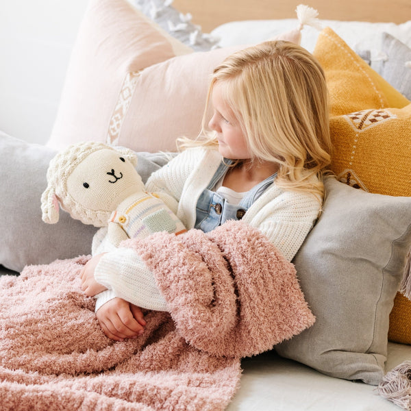 Little girl laying in bed with beautiful decorations, wrapped in super soft and stretchy light pink RIBBED BAMBONI TODDLER BLANKETS - Saranoni