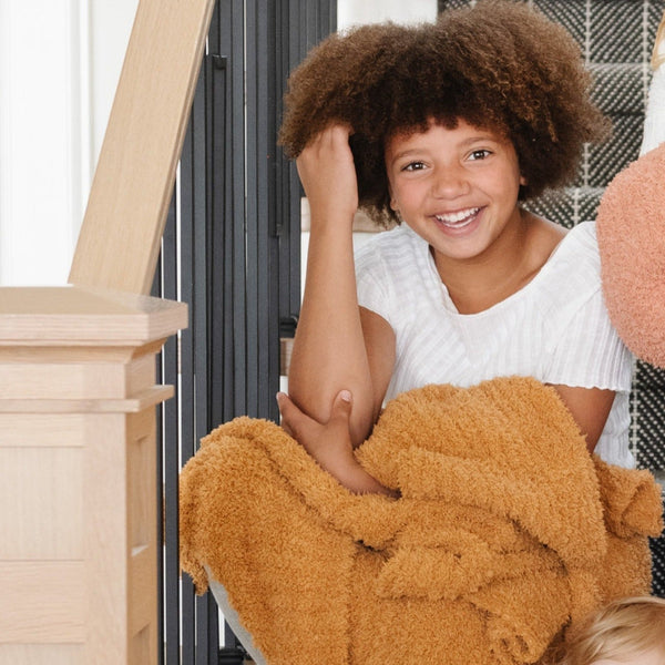 Young girl smiling with her beautiful, soft and stretchy Golden RIBBED BAMBONI TODDLER BLANKETS - Saranoni