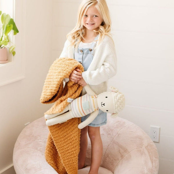 Adorable little girl holding her stuffed animal and beautiful Golden RIBBED BAMBONI TODDLER BLANKETS - Saranoni