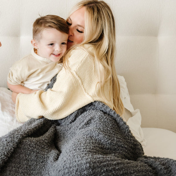 Mom and son snuggled together in bed with beautiful and soft Charcoal RIBBED BAMBONI XL BLANKETS - Saranoni