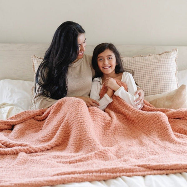 Mom and daughter snuggling together under pink/peach Sunkissed RIBBED BAMBONI® XL BLANKETS - Saranoni