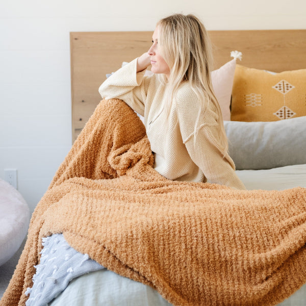 Woman sitting on beautiful bed with her cozy soft Golden Yellow RIBBED BAMBONI XL BLANKETS - Saranoni