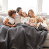 Family snuggled together on the couch with their cozy and soft, warm and breathable Charcoal RIBBED BAMBONI XL BLANKETS - Saranoni