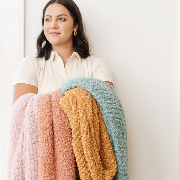 Woman holding out four beautiful colors of RIBBED BAMBONI XL BLANKETS - Saranoni