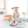 A little girl sits on a Luxury Receiving Dew (light blue) Colored Lush Saranoni Blanket. The soft blanket is a small blanket and a baby blanket or toddler blanket.