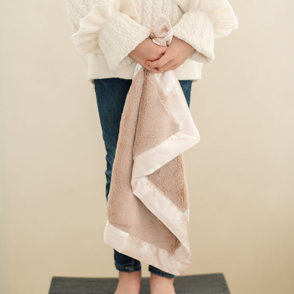 Mini blanket with a plush, velvety feel and a smooth satin border, perfect for a cozy wrap with a touch of elegance.