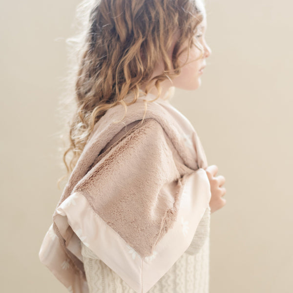 Little girl holding a soft and soothing receiving blanket, designed to keep warm and comfortable.