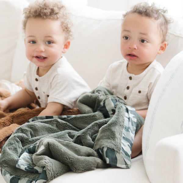 Young boys snuggled up with soft and inviting green and tan toddler blankets with a satin back, providing a gentle, warm embrace with a luxurious, smooth feel for ultimate comfort.