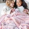 Elegant pink satin-backed toddler blanket, offering a combination of plush comfort and a sleek, silky finish.