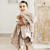 Little boy wrapped up with a cozy tan colored toddler blanket. 