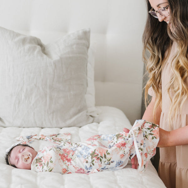 Mom wrapping up newborn baby girl in floral STRETCHY SWADDLES - Saranoni