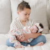 Older brother holding newborn sister in floral print STRETCHY SWADDLES - Saranoni