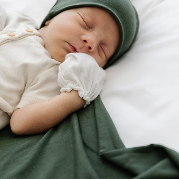 Baby laying on green STRETCHY SWADDLES with matching hat- Saranoni