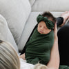 Adorable baby being rocked to sleep by mom. Wrapped in green STRETCHY SWADDLES - Saranoni