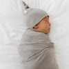 Adorable baby boy falling asleep in grey STRETCHY SWADDLES - Saranoni