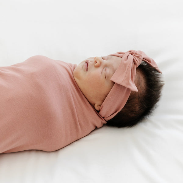 Adorable baby girl falling asleep in rosy pink STRETCHY SWADDLES - Saranoni