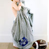 A little boy holds a Luxury Toddler Gray Colored Lush Saranoni Blanket. The soft blanket is a toddler blanket or baby blanket and has a soft faux fur feeling. The blanket has the Utah State University Logo on it.