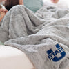 A Luxury Extra Large Throw Gray Colored Patterned Faux Fur Saranoni Blanket. The soft blanket is an oversized throw blanket and has a soft faux fur feeling. The blanket has a Utah State University Logo on it.