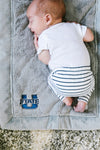 A baby lays on a Luxury Mini Gray Colored Lush Saranoni Blanket. The soft blanket is a small blanket and a toddler or baby blanket and has a soft faux fur feeling. The blanket has the Utah State University Logo on it.