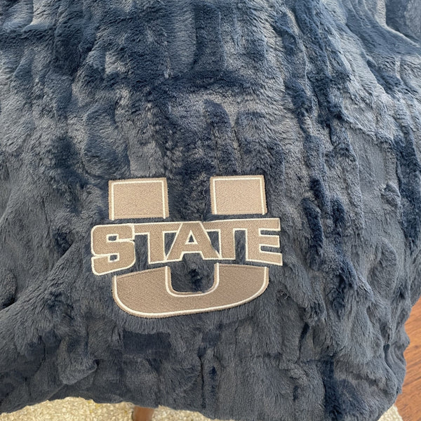 A Luxury Throw Midnight (dark blue) Colored Patterned Faux Fur Saranoni Blanket. The soft blanket is a throw blanket and has a soft faux fur feeling. The blanket has a Utah State University Logo on it.